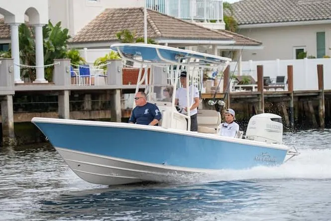 Slide: The Image of 2026 Sea Chaser 23 LX boat with blue hull and white interior at a showroom. - 1