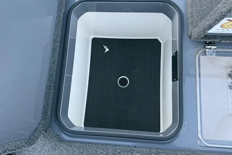 Slide: The Image of 2021 Vexus VX20 boat storage compartment with drain plug and carpeted interior. - 26
