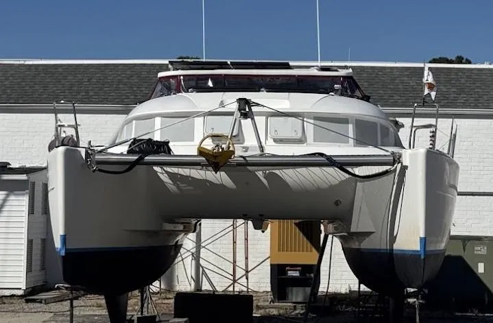 The Image of 2004 Lagoon 380 catamaran on dry dock, front view, against a clear blue sky. - 0