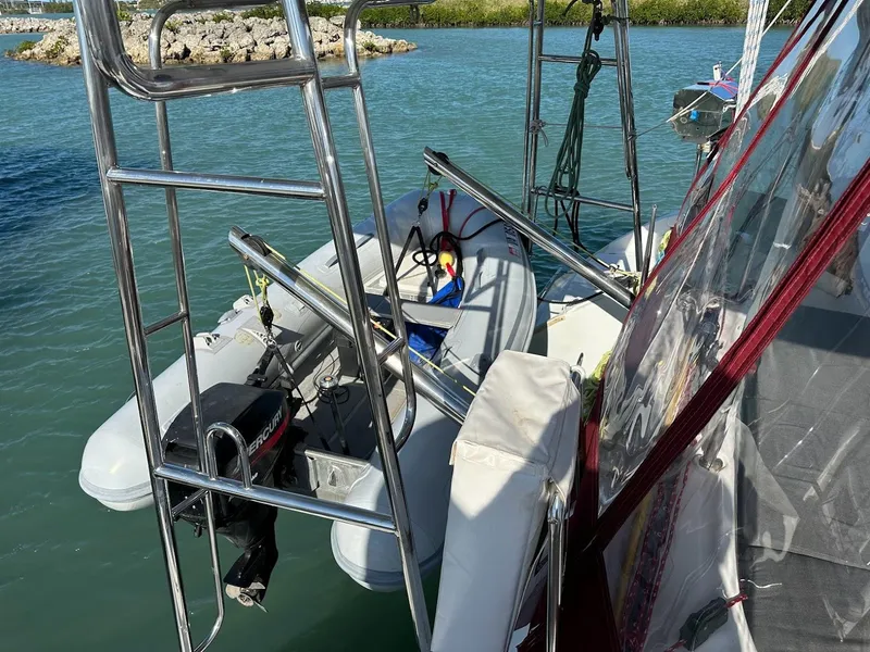 Slide: The Image of Lagoon 380 catamaran with dinghy and outboard motor, docked in a serene marina, 2004 model. - 10