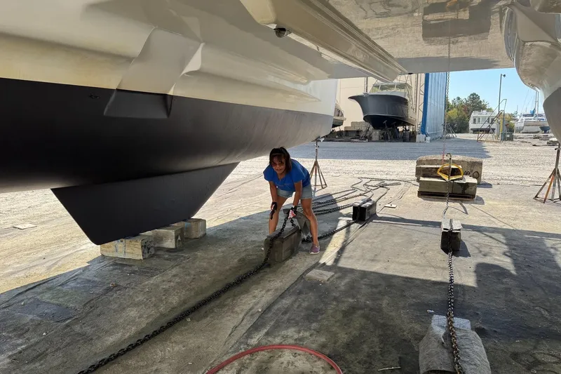 Slide: The Image of Person working on a 2004 Lagoon 380 catamaran in a boatyard. - 6