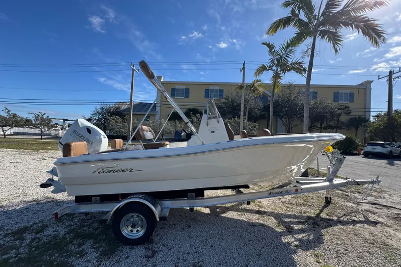 The Image of 2026 Pioneer 180 Islander boat on trailer, parked outdoors under clear blue sky. - 0