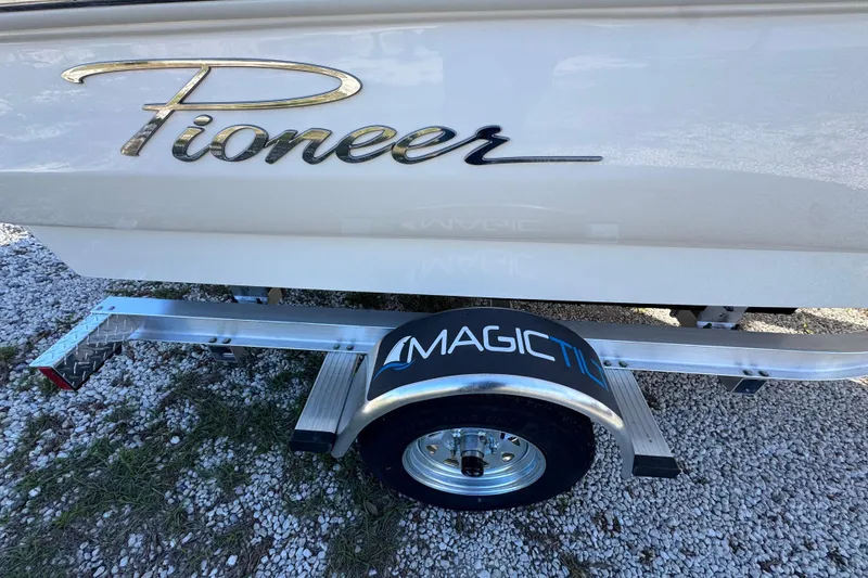 Slide: The Image of 2026 Pioneer 180 Islander boat on Magic Tilt trailer, parked on gravel. - 14