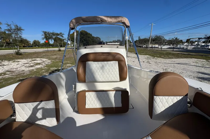 Slide: The Image of 2026 Pioneer 180 Islander boat interior with brown and white seating, clear blue sky. - 7