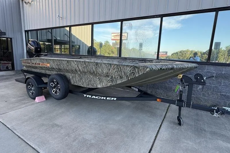 The Image of 2026 Tracker Grizzly 1756 T Marsh boat on trailer, camo design, parked outside building. - 1