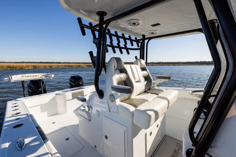 Slide: The Image of 2023 Freeman 34VH boat interior with luxurious seating and fishing rod holders on a sunny day. - 15