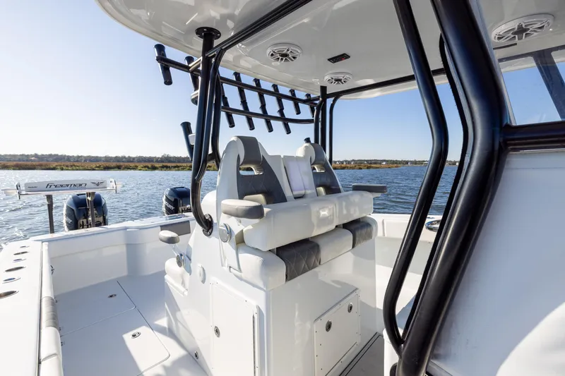Slide: The Image of 2023 Freeman 34VH boat interior with seating and rod holders on a sunny day. - 16