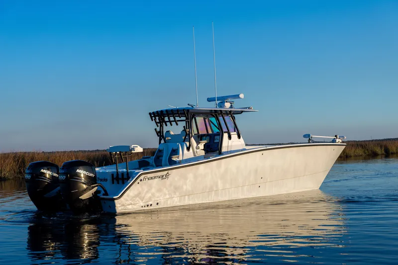Slide: The Image of 2023 Freeman 34VH boat on calm water, featuring dual Mercury engines. - 2
