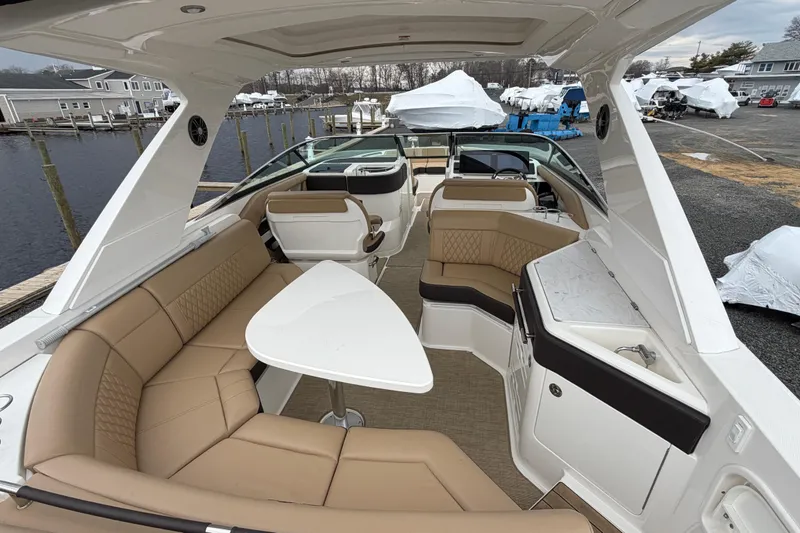 Slide: The Image of 2023 Sea Ray SLX 310 Outboard interior with luxurious seating and table, docked at marina. - 10