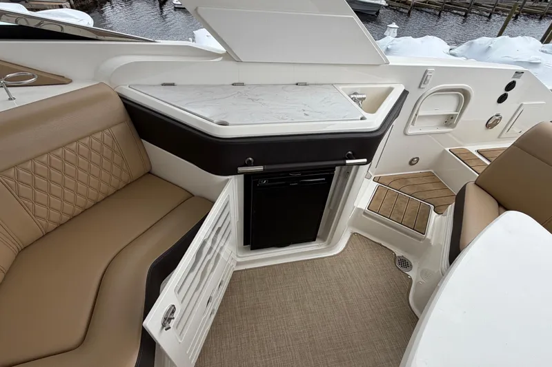 Slide: The Image of 2023 Sea Ray SLX 310 Outboard interior with seating, kitchenette, and storage. - 13