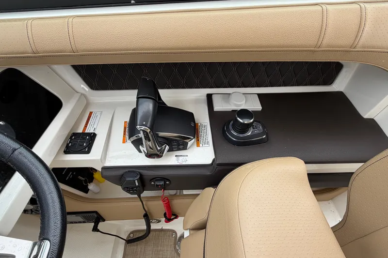 Slide: The Image of 2023 Sea Ray SLX 310 Outboard helm with controls and beige seating. - 19