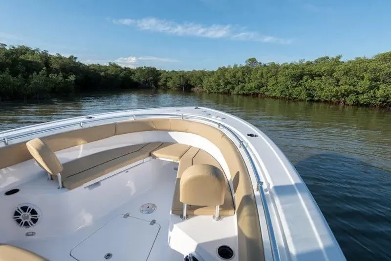 Slide: The Image of 2026 Sportsman Open 252 Center Console boat on calm water near lush greenery. - 19