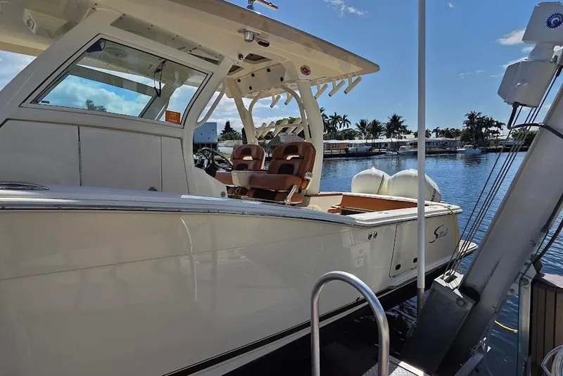 Slide: The Image of 2015 Scout 350 LXF boat docked by a serene waterfront with clear skies. - 11