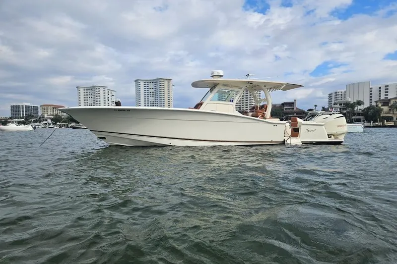 Slide: The Image of 2015 Scout 350 LXF boat on water with city skyline background. - 2
