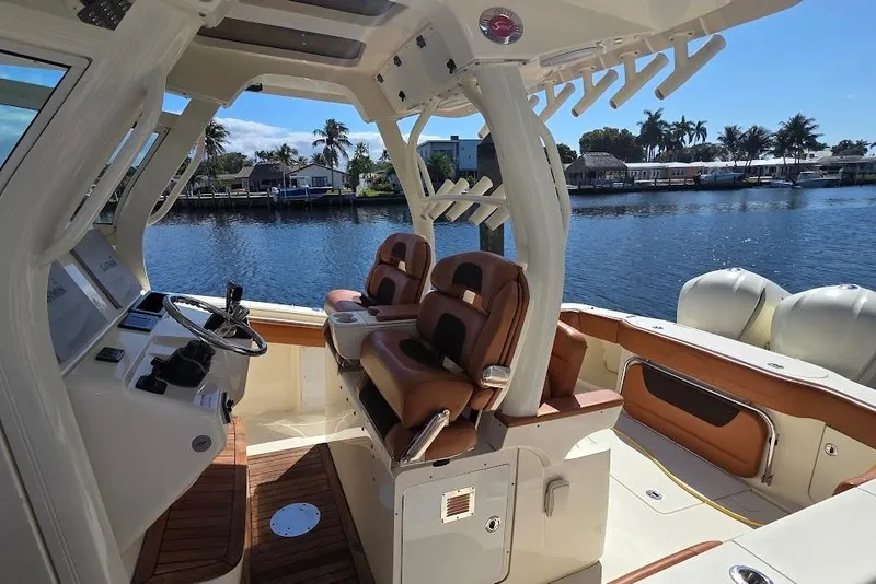 Slide: The Image of 2015 Scout 350 LXF boat interior with leather seats, steering console, and waterfront view. - 21