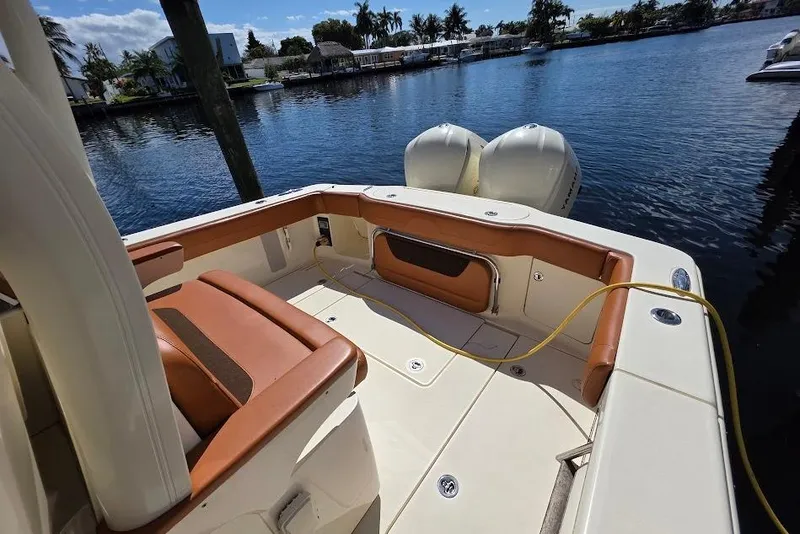 Slide: The Image of 2015 Scout 350 LXF boat interior with tan seating, docked by a serene waterfront. - 25