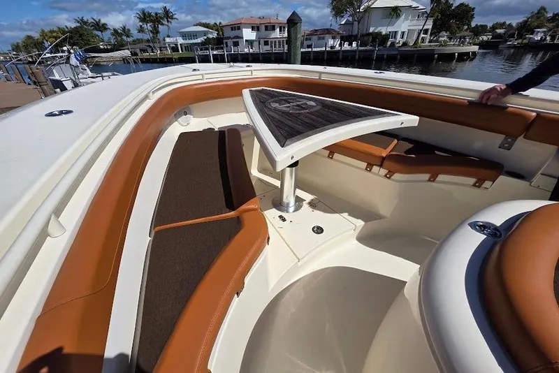 Slide: The Image of 2015 Scout 350 LXF boat interior with cushioned seating and table, docked by waterfront homes. - 35