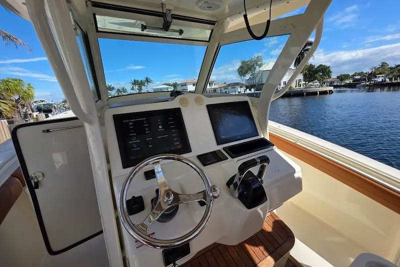 Slide: The Image of 2015 Scout 350 LXF boat helm with dual screens, steering wheel, and waterfront view. - 45
