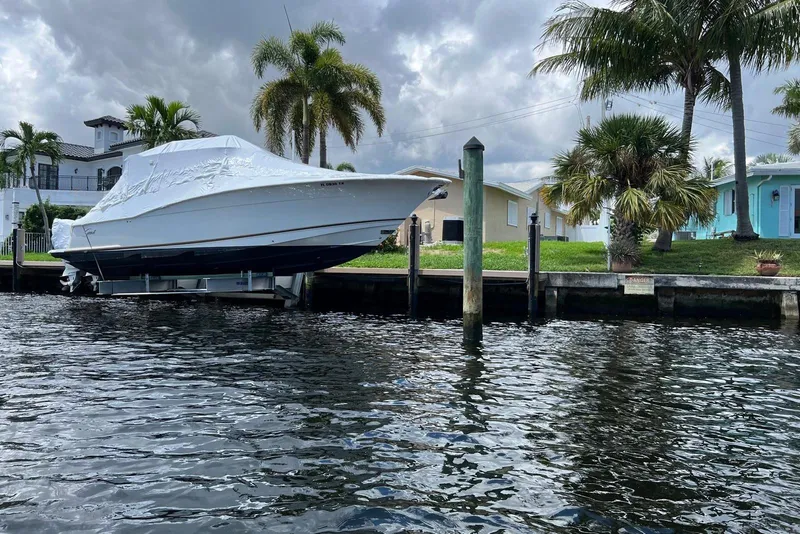 Slide: The Image of 2015 Scout 350 LXF boat covered and docked by waterfront homes with palm trees. - 5