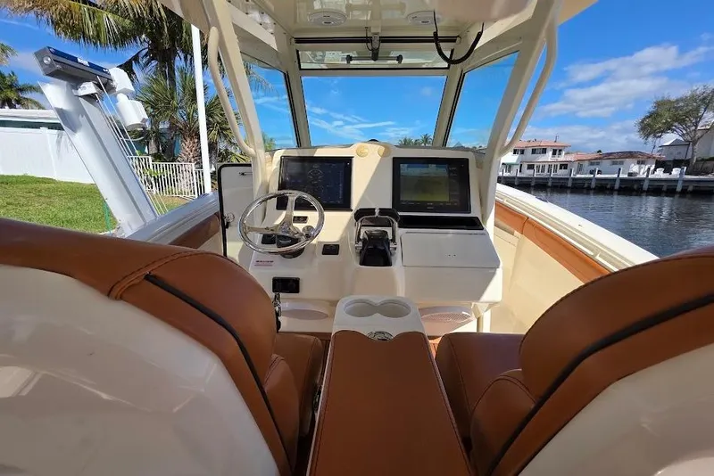 Slide: The Image of 2015 Scout 350 LXF boat cockpit with dual screens and leather seating, near waterfront homes. - 54