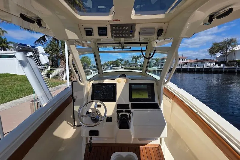 Slide: The Image of 2015 Scout 350 LXF boat cockpit with modern navigation system, docked by waterfront homes. - 55