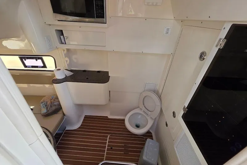 Slide: The Image of Interior of 2015 Scout 350 LXF boat featuring a compact bathroom with toilet and wooden flooring. - 67