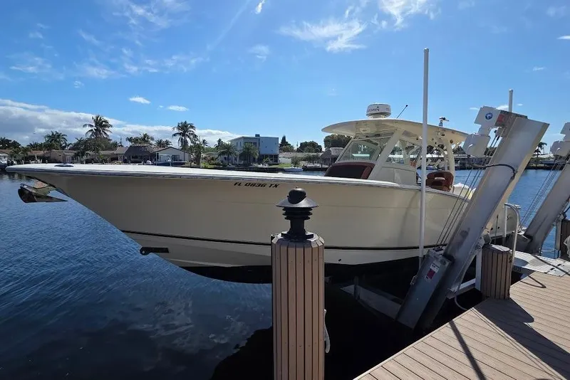 Slide: The Image of 2015 Scout 350 LXF boat docked on a sunny day, surrounded by water and palm trees. - 7