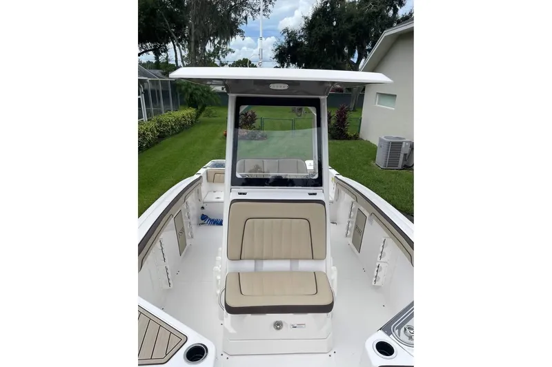 Slide: The Image of 2022 Yamaha Boats 252 FSH Sport interior with seating and console, in a residential setting. - 8