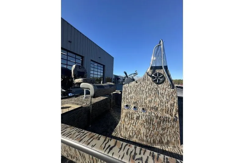 Slide: The Image of 2026 Xpress H190B Bay boat with camouflage design, parked outdoors under clear blue sky. - 9