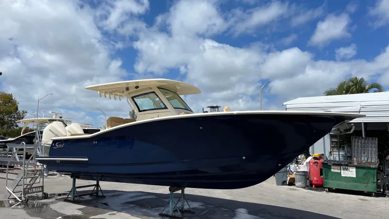 The Image of Scout 305 LXF 2026 boat on a trailer under blue sky. - 0
