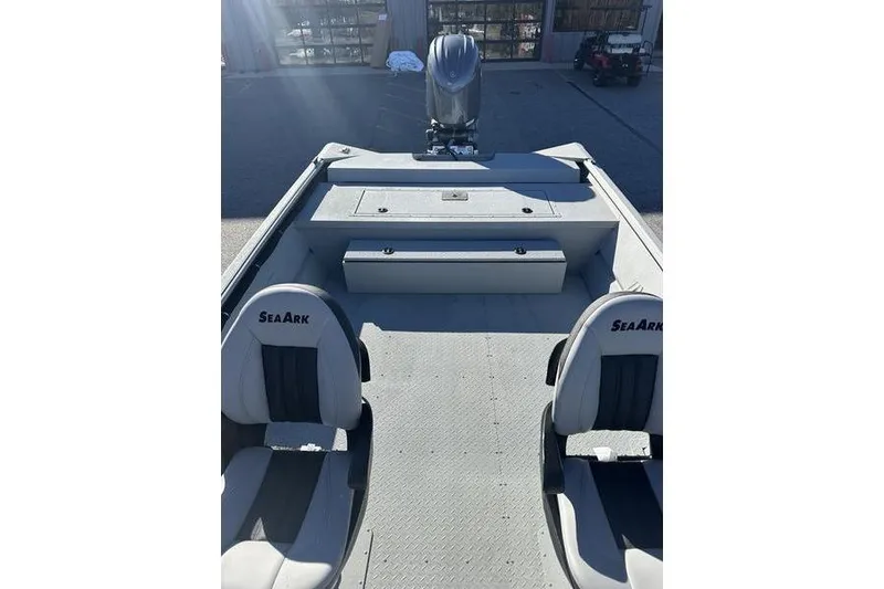 Slide: The Image of 2025 SeaArk 2072 MVT boat interior with seating and motor, parked outdoors. - 13