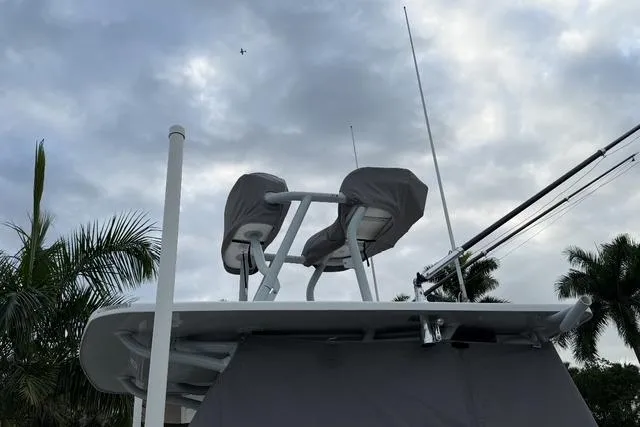 Slide: The Image of 2024 SeaHunter 28 Floridian boat with covered seats, set against a cloudy sky and palm trees. - 6