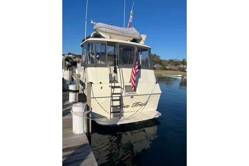 Slide: The Image of 1991 Hatteras 40 Motor Yacht docked, displaying American flag, clear blue sky. - 107