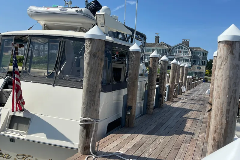 Slide: The Image of 1991 Hatteras 40 Motor Yacht docked at a marina with wooden posts and waterfront homes. - 108