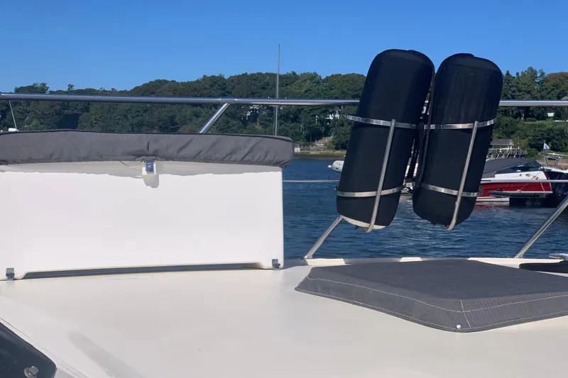 Slide: The Image of 1991 Hatteras 40 Motor Yacht deck with cushions and fenders, docked by a scenic shoreline. - 109