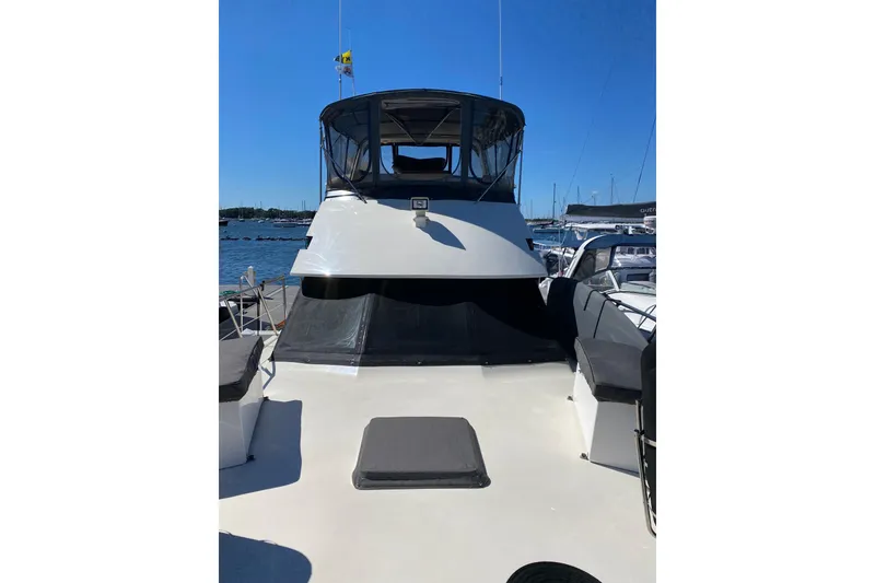 Slide: The Image of 1991 Hatteras 40 Motor Yacht docked, featuring spacious deck and covered helm area. - 11