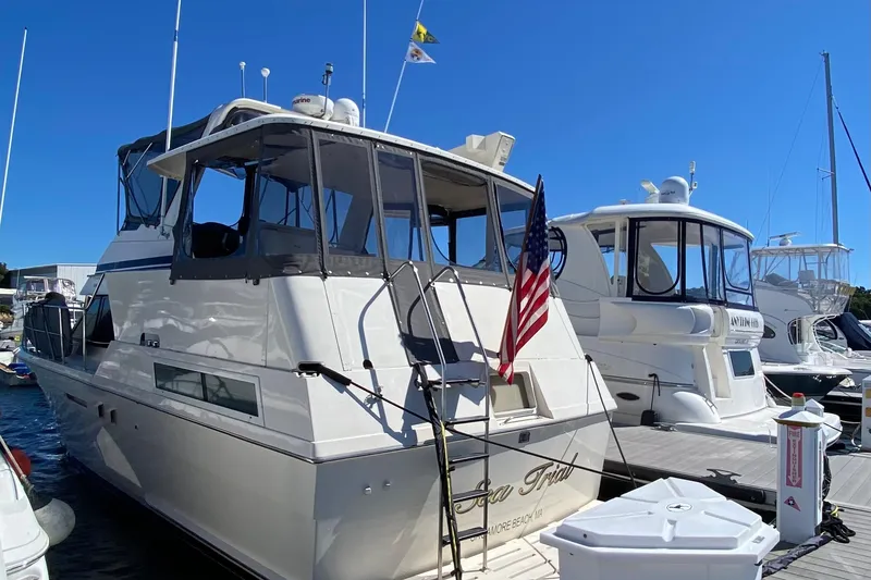 Slide: The Image of 1991 Hatteras 40 Motor Yacht docked, featuring American flag and clear blue sky. - 15