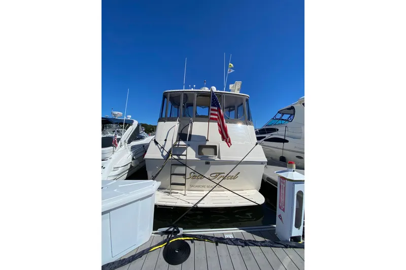 Slide: The Image of 1991 Hatteras 40 Motor Yacht docked, displaying American flag under clear blue sky. - 16