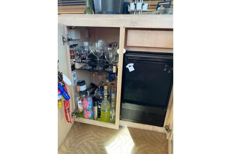 Slide: The Image of Bar cabinet with glassware and bottles inside a 1991 Hatteras 40 Motor Yacht. - 18