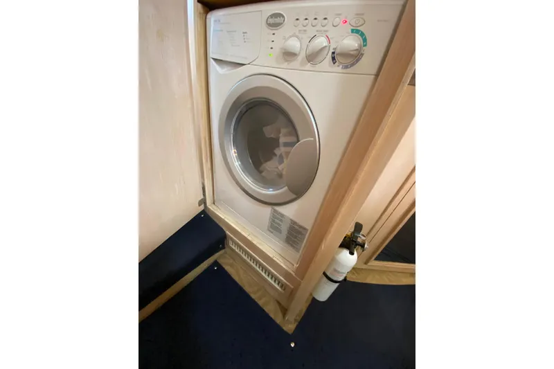 Slide: The Image of Laundry area inside 1991 Hatteras 40 Motor Yacht, featuring a compact washing machine. - 55