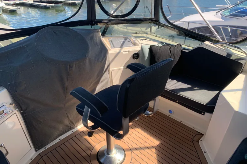 Slide: The Image of 1991 Hatteras 40 Motor Yacht helm with seating, covered controls, and marina view. - 62