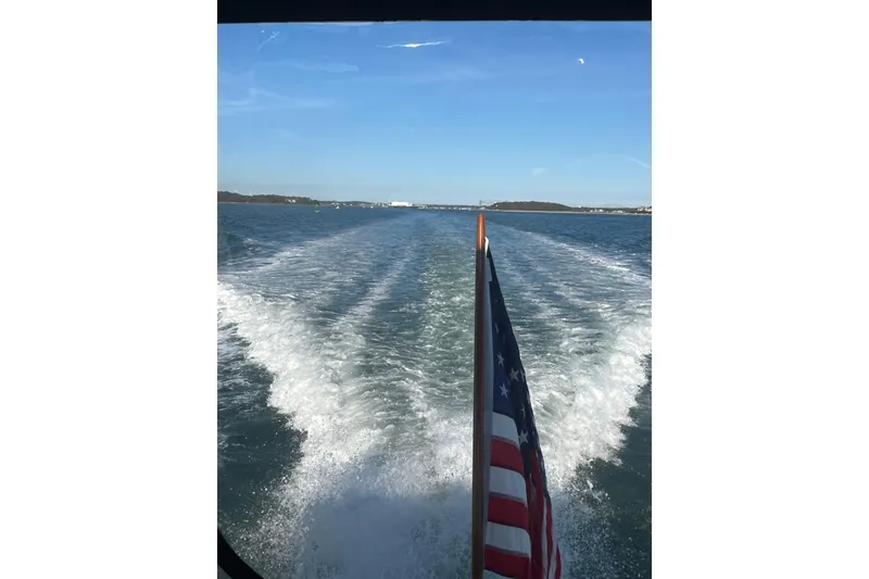 Slide: The Image of Wake of a 1991 Hatteras 40 Motor Yacht with American flag on open water. - 9