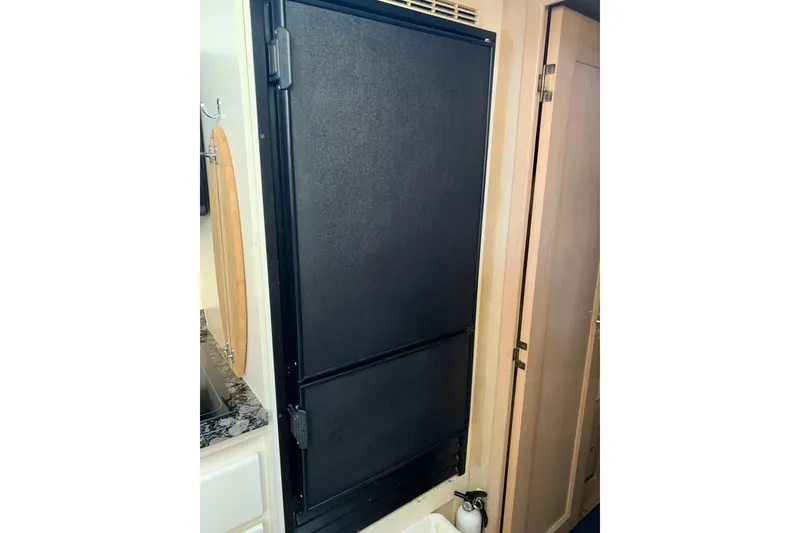 Slide: The Image of 1991 Hatteras 40 Motor Yacht interior with black refrigerator and wooden cabinetry. - 98