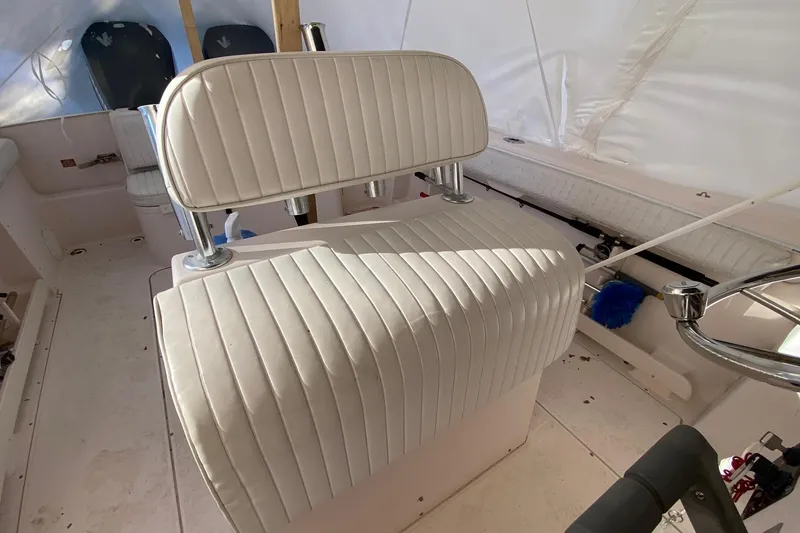 Slide: The Image of 1999 Grady-White Chase 263 boat interior with white cushioned seating and steering wheel. - 13