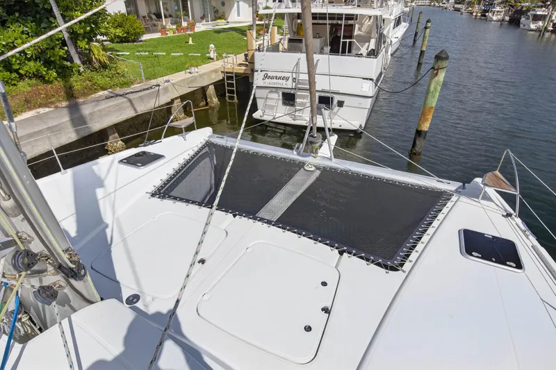 Slide: The Image of 2014 Fountaine Pajot Helia 44 catamaran docked at a marina, featuring spacious deck and netting. - 29