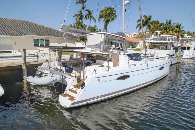 Slide: The Image of 2014 Fountaine Pajot Helia 44 catamaran docked near palm trees and waterfront homes. - 76