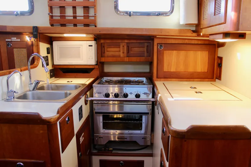 Slide: The Image of 1997 Valiant 39 yacht kitchen with stove, sink, and microwave in wooden cabinetry. - 45