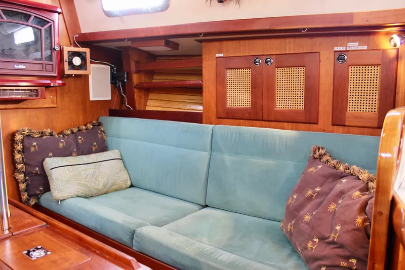 Slide: The Image of 1997 Valiant 39 yacht interior with teal sofa, decorative pillows, and wooden cabinetry. - 68