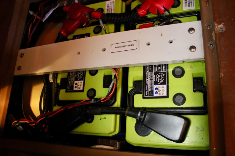 Slide: The Image of House batteries in a 1997 Valiant 39, featuring green casing and wiring connections. - 82