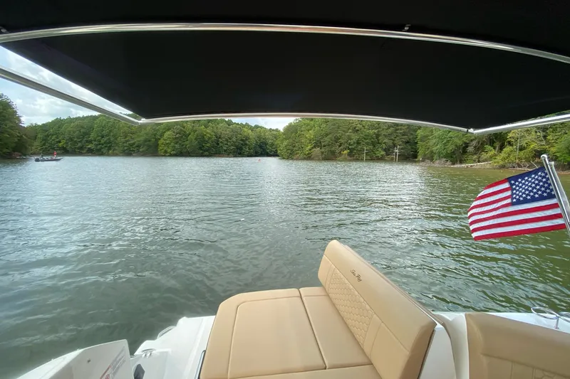 Slide: The Image of 2020 Sea Ray Sundancer 320 on a serene lake with American flag and lush trees. - 5